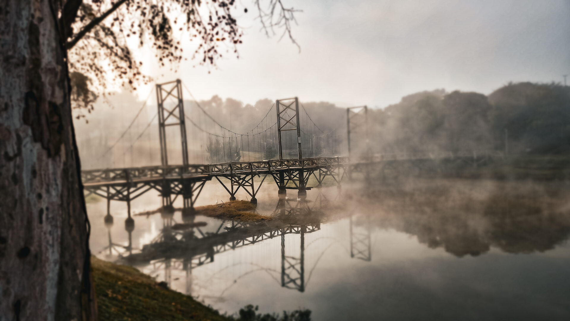 Ponte pênsil sobre o lago coberto de névoa ao amanhecer